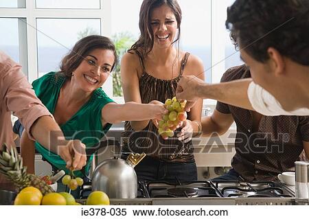 Friends eating fruit in kitchen View Large Photo Image Stock Photography - Friends eating fruit in kitchen. Fotosearch
