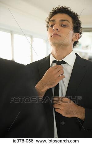 Man adjusting tie in mirror View Large Photo Image Stock Photograph - Man adjusting tie in mirror. Fotosearch