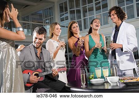 Stock Photograph - Man playing a ukelele at party. Fotosearch