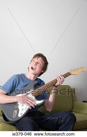 A teenage boy playing the guitar View Large Photo Image Stock Photograph - A teenage boy playing the guitar. Fotosearch