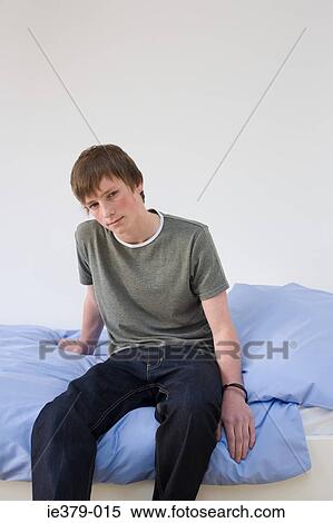 Portrait of a teenage boy sat on a bed View Large Photo Image Stock Photography - Portrait of a teenage boy sat on a bed. Fotosearch