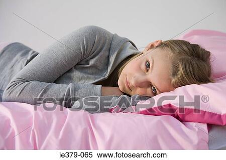 Stock Photography - Portrait of a teenage girl lying on her bed. Fotosearch