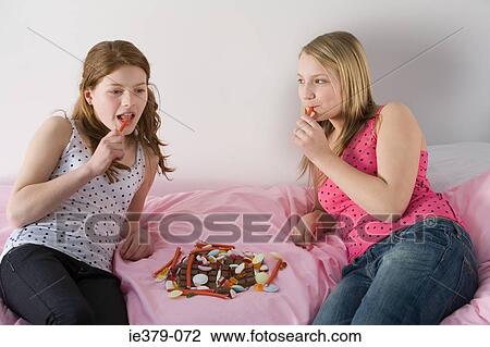 Stock Image - Teenage girls eating sweets. Fotosearch