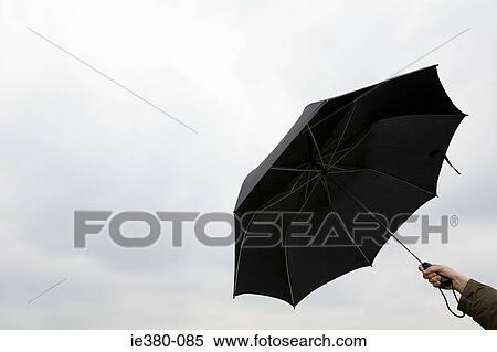 Stock Photography - Person holding black umbrella against the rain. Fotosearch