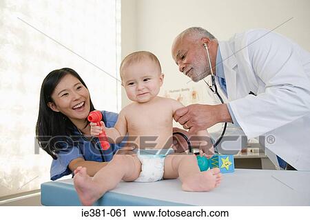 Stock Image - A doctor and nurse examining a baby. Fotosearch