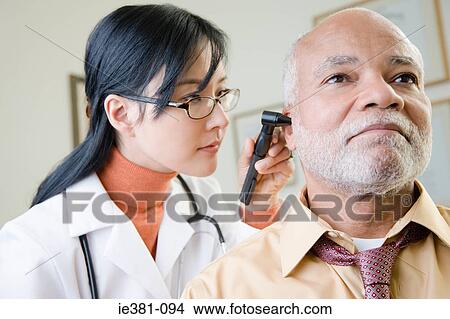 A doctor examining a patients ear View Large Photo Image Picture - A doctor examining a patients ear. Fotosearch