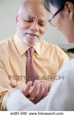 A doctor examining a patients hand View Large Photo Image Stock Image - A doctor examining a patients hand. Fotosearch