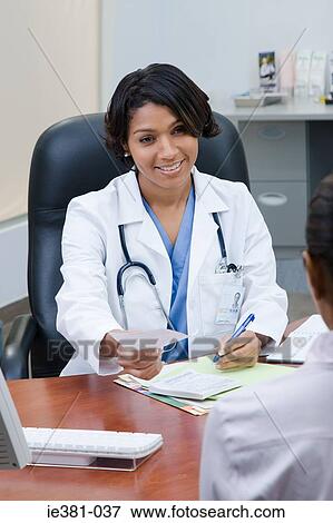 A doctor handing a patient a prescription View Large Photo Image Stock Photo - A doctor handing a patient a prescription. Fotosearch