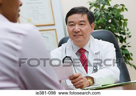 A doctor handing a patient a prescription View Large Photo Image Stock Photo - A doctor handing a patient a prescription. Fotosearch