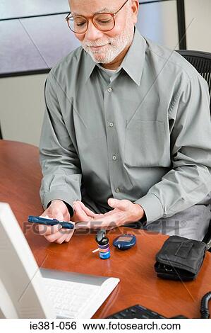 Stock Photograph - A man doing a home blood glucose testing . Fotosearch