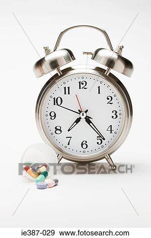 Alarm clock and a container of tablets View Large Photo Image Stock Photo - Alarm clock and a container of tablets. Fotosearch