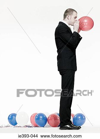 Picture - Man blowing up balloon. Fotosearch