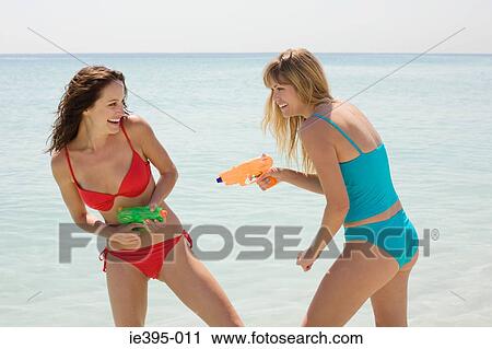 Stock Image - Friends having a water fight. Fotosearch