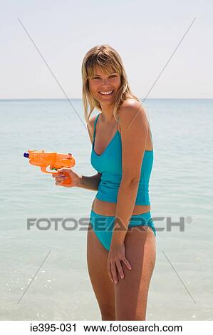 Stock Image - Portrait of a woman holding a waterpistol. Fotosearch