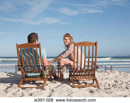 Stock Photo - Couple on lounge chairs on the beach. Fotosearch