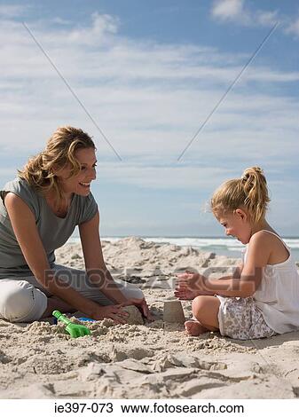 Mother and daughter playing in sand View Large Photo Image Stock Image - Mother and daughter playing in sand. Fotosearch