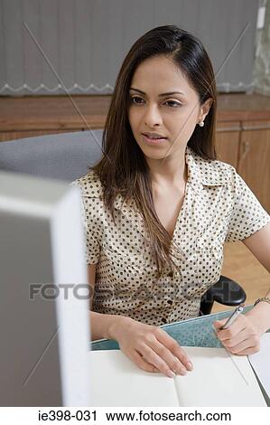 Stock Image - Female office worker at desk. Fotosearch