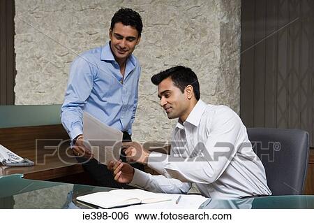 Stock Photograph - Male colleagues reading a document. Fotosearch