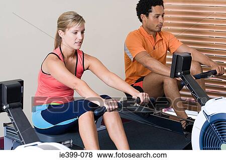 Woman and man on rowing machines View Large Photo Image Stock Photo - Woman and man on rowing machines. Fotosearch