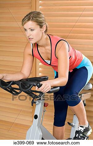 Woman on exercise bike View Large Photo Image Stock Photo - Woman on exercise bike. Fotosearch
