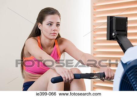 Woman on rowing machine View Large Photo Image Stock Photograph - Woman on rowing machine. Fotosearch