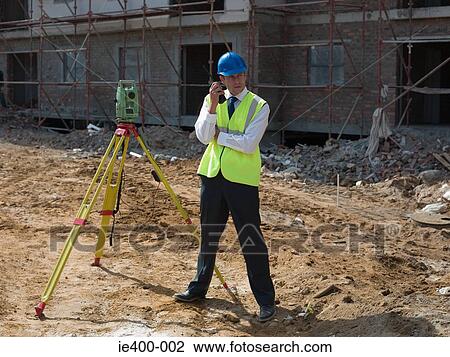 Stock Image - Engineer with theodolite and walkie talkie. Fotosearch