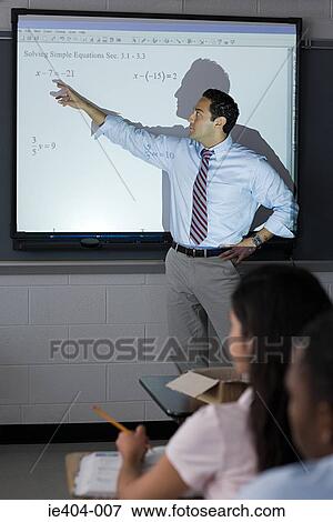 A teacher pointing to sums on a projection screen View Large Photo Image Stock Photo - A teacher pointing to sums on a projection screen. Fotosearch