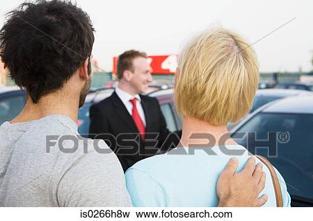 A couple with a salesman at a car dealership View Large Photo Image Stock Photo - A couple with a salesman at a car dealership. Fotosearch