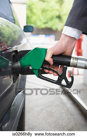 Stock Photo - A man filling a car with petrol. Fotosearch