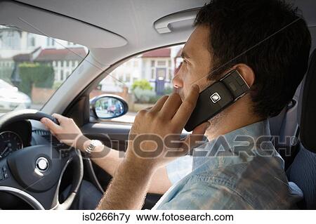 Stock Photo - A man using a cell phone in a car. Fotosearch