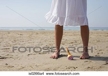 Picture - Woman dropping her ice cream on beach. Fotosearch