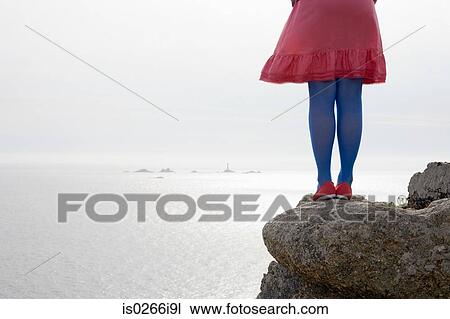 Stock Image - Woman in blue tights standing on rocks. Fotosearch