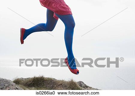 Stock Image - Woman jumping on rocks. Fotosearch