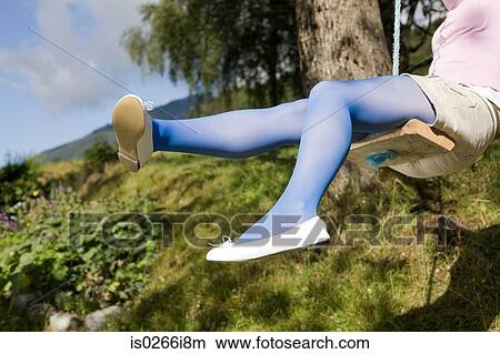 Picture - Young woman playing on a swing. Fotosearch