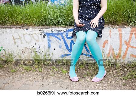 Young woman sitting on wall texting View Large Photo Image Stock Image - Young woman sitting on wall texting. Fotosearch