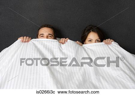 Stock Image - A couple hiding under a duvet. Fotosearch