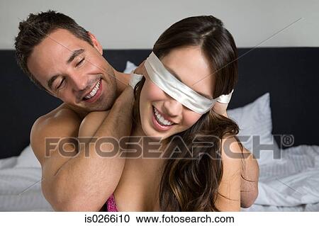 Stock Image - A man blindfolding a woman. Fotosearch