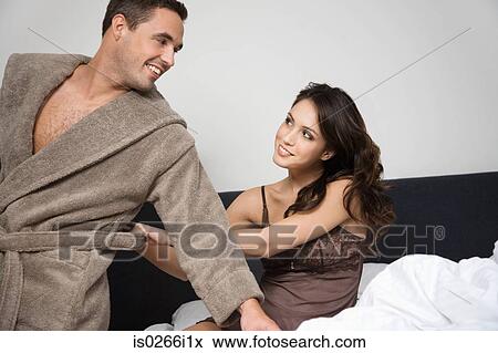 Stock Photo - A woman pulling at a mans bathrobe. Fotosearch