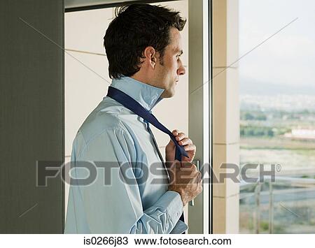 A businessman tying his tie View Large Photo Image Stock Image - A businessman tying his tie. Fotosearch