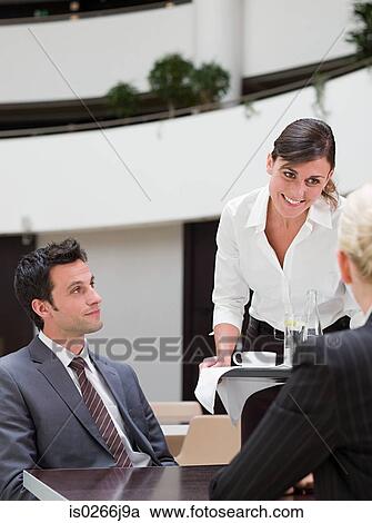 Stock Image - A waitress serving business people. Fotosearch