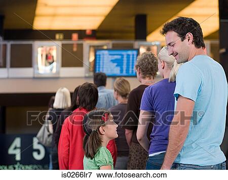 Stock Photo - A father and daughter waiting in a queue at the cinema. Fotosearch