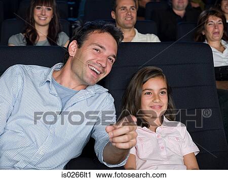 Stock Image - Father and daughter watching a movie. Fotosearch