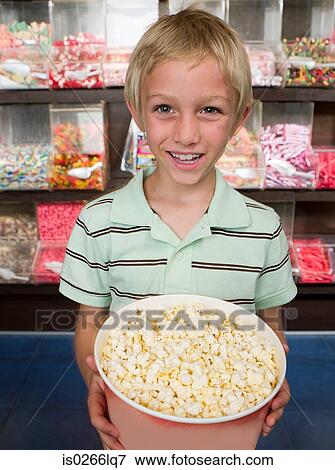 Portrait of a boy holding a tub of popcorn View Large Photo Image Stock Photo - Portrait of a boy holding a tub of popcorn. Fotosearch