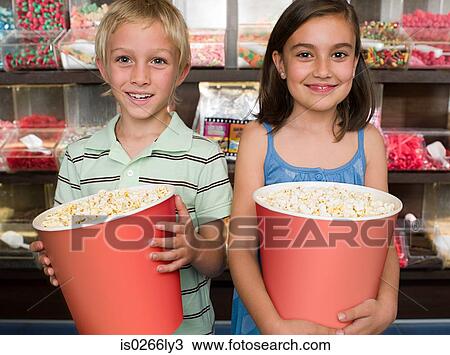 Two children holding tubs of popcorn View Large Photo Image Stock Image - Two children holding tubs of popcorn. Fotosearch