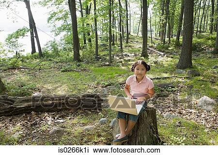 A girl using a laptop in a forest View Large Photo Image Stock Image - A girl using a laptop in a forest. Fotosearch