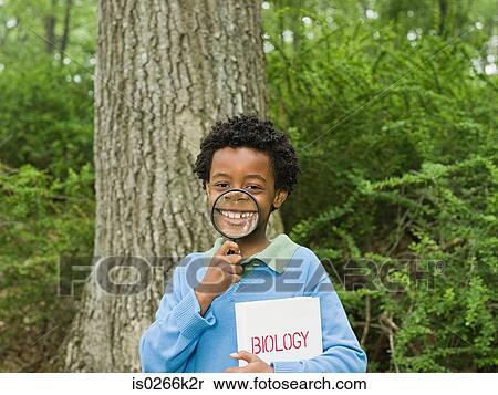 Portrait of a boy holding a book and a magnifying glass View Large Photo Image Stock Photography - Portrait of a boy holding a book and a magnifying glass. Fotosearch
