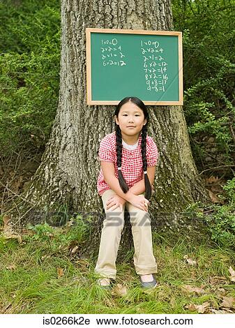 Stock Image - Portrait of a girl and a blackboard of sums. Fotosearch