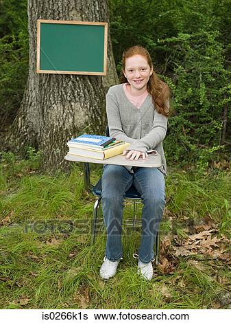 Stock Photograph - Portrait of a girl sat a desk. Fotosearch