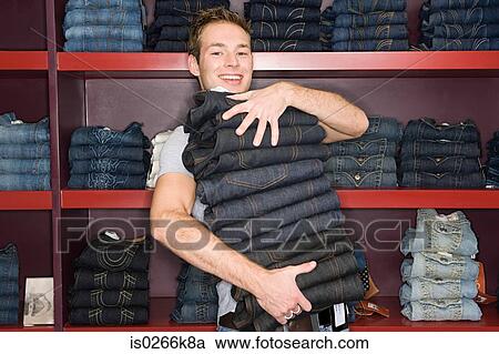 Man holding a stack of jeans View Large Photo Image Stock Image - Man holding a stack of jeans. Fotosearch