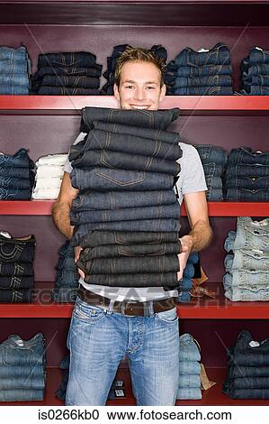 Man holding a stack of jeans View Large Photo Image Stock Image - Man holding a stack of jeans. Fotosearch